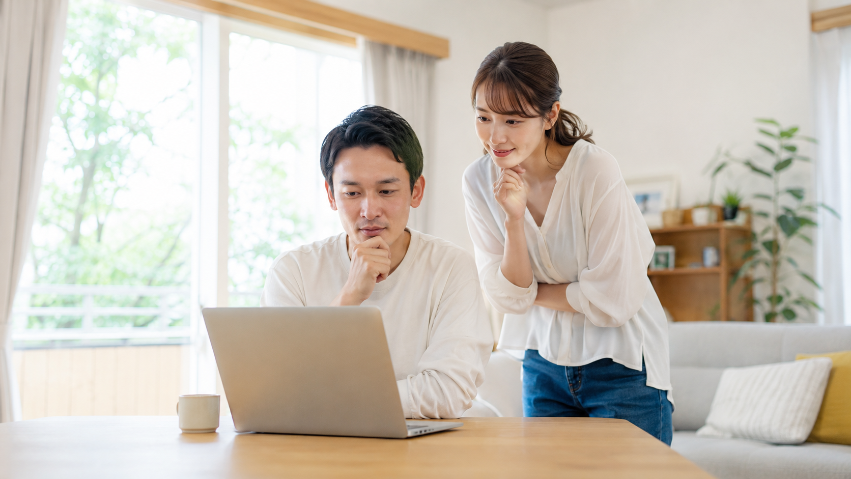 ノートPCを見て温泉宿を探している笑顔の日本人夫婦